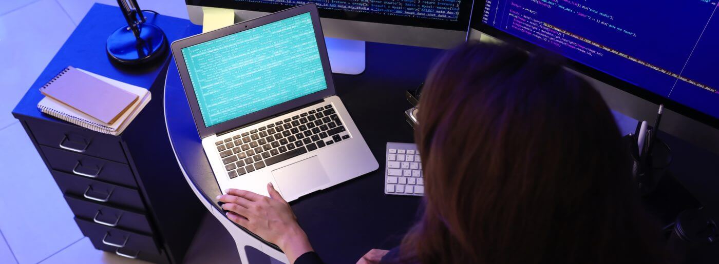 Back of woman's head looking at laptop computer working her IT job