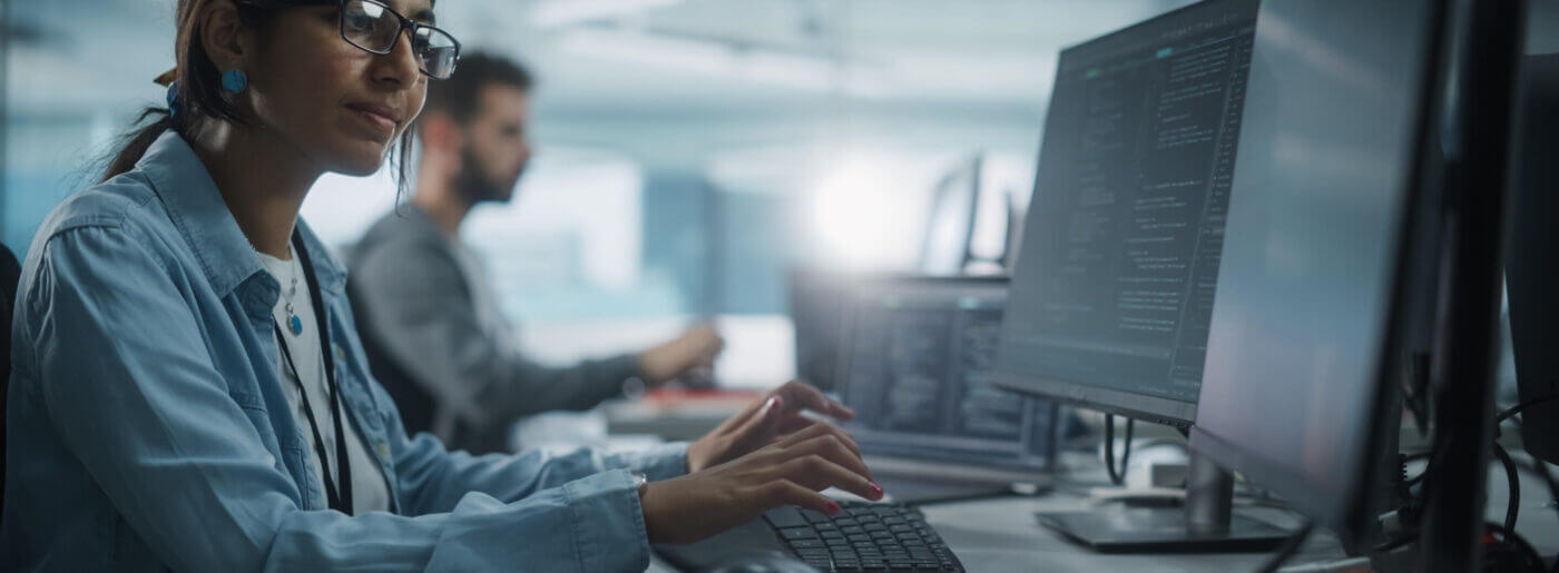 Woman typing at desktop computer working on engineering efficiency 