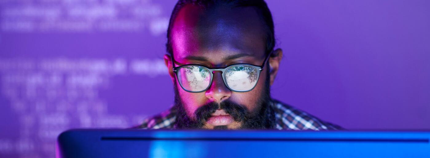 Face of man wearing glasses looking at computer screen for DevOps