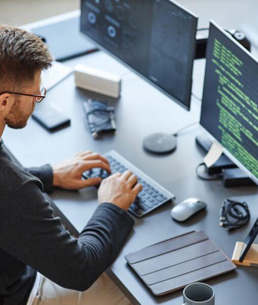 Man in glasses typing on desktop computer working on ITOps services