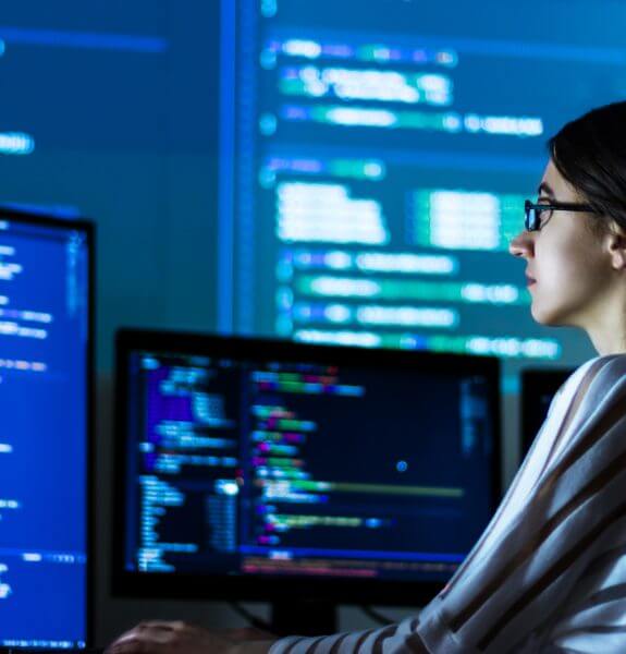 Woman in glasses looking at computer screen working on secops services